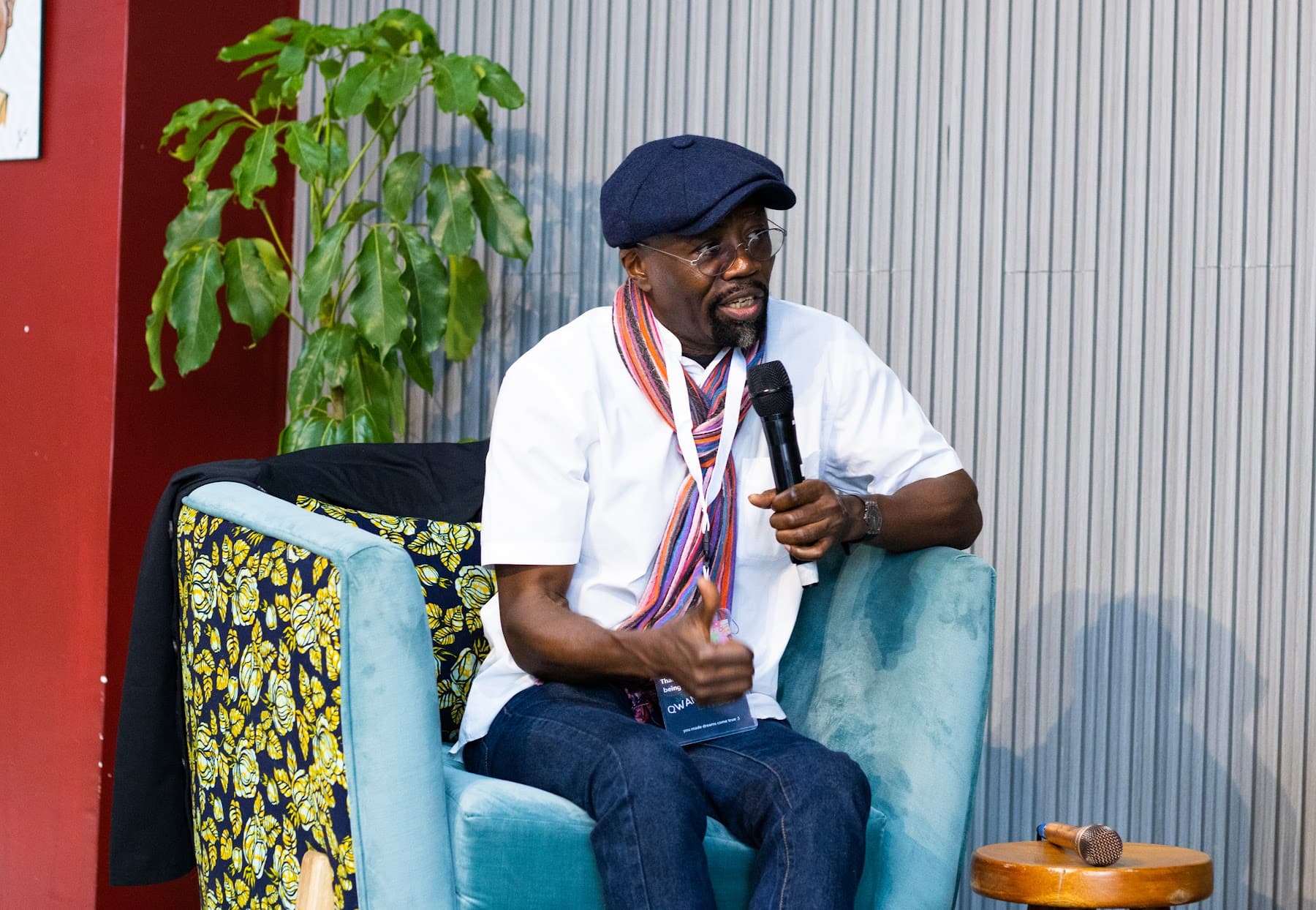 A panellist in a flat cap and striped scarf speaking into a microphone